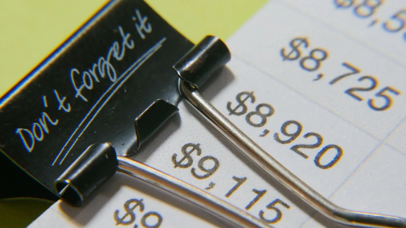 Close-up image showcasing a binder clip on a detailed financial report with highlighted amounts.