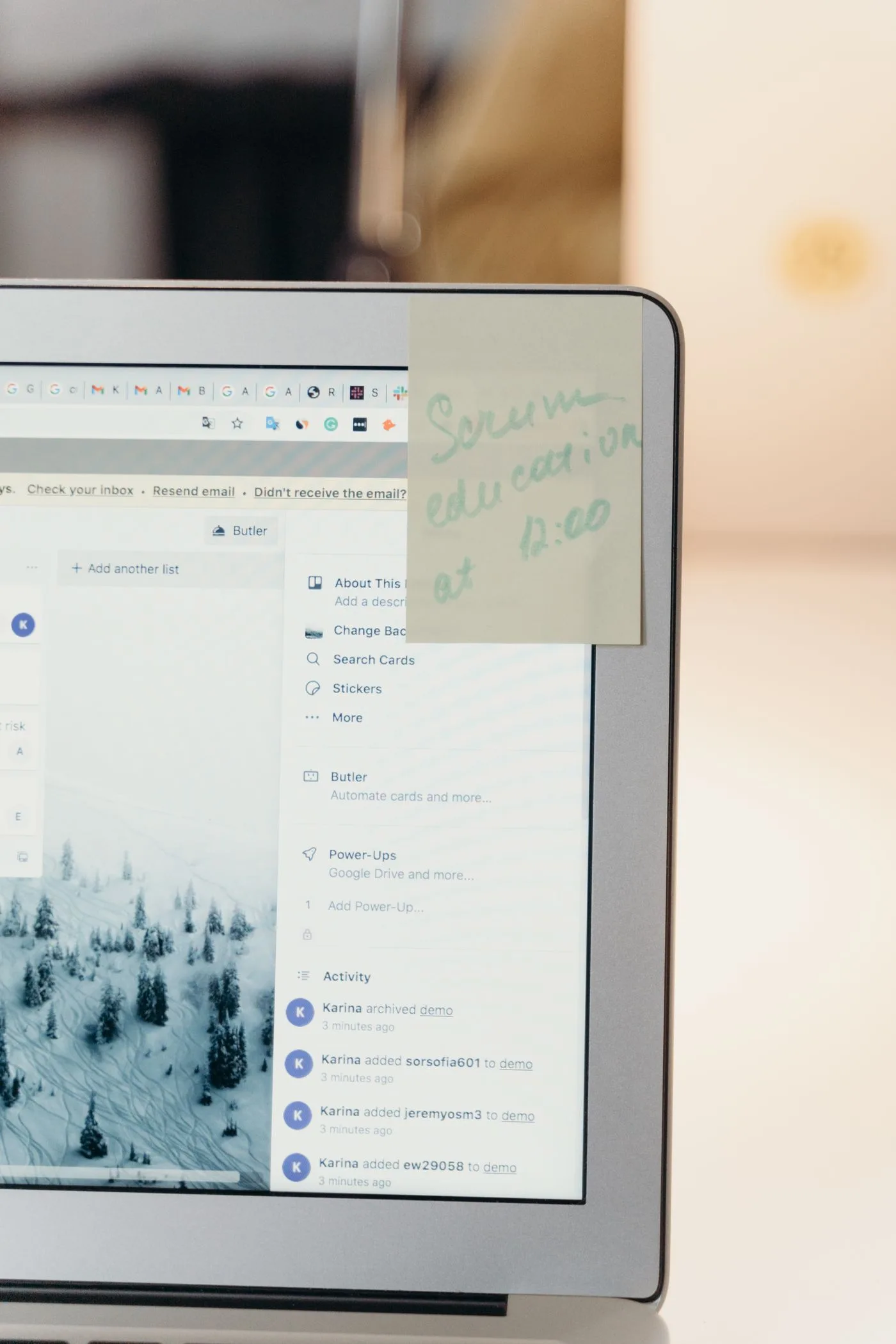 Close-up of a laptop screen with a handwritten sticky note reminder attached.