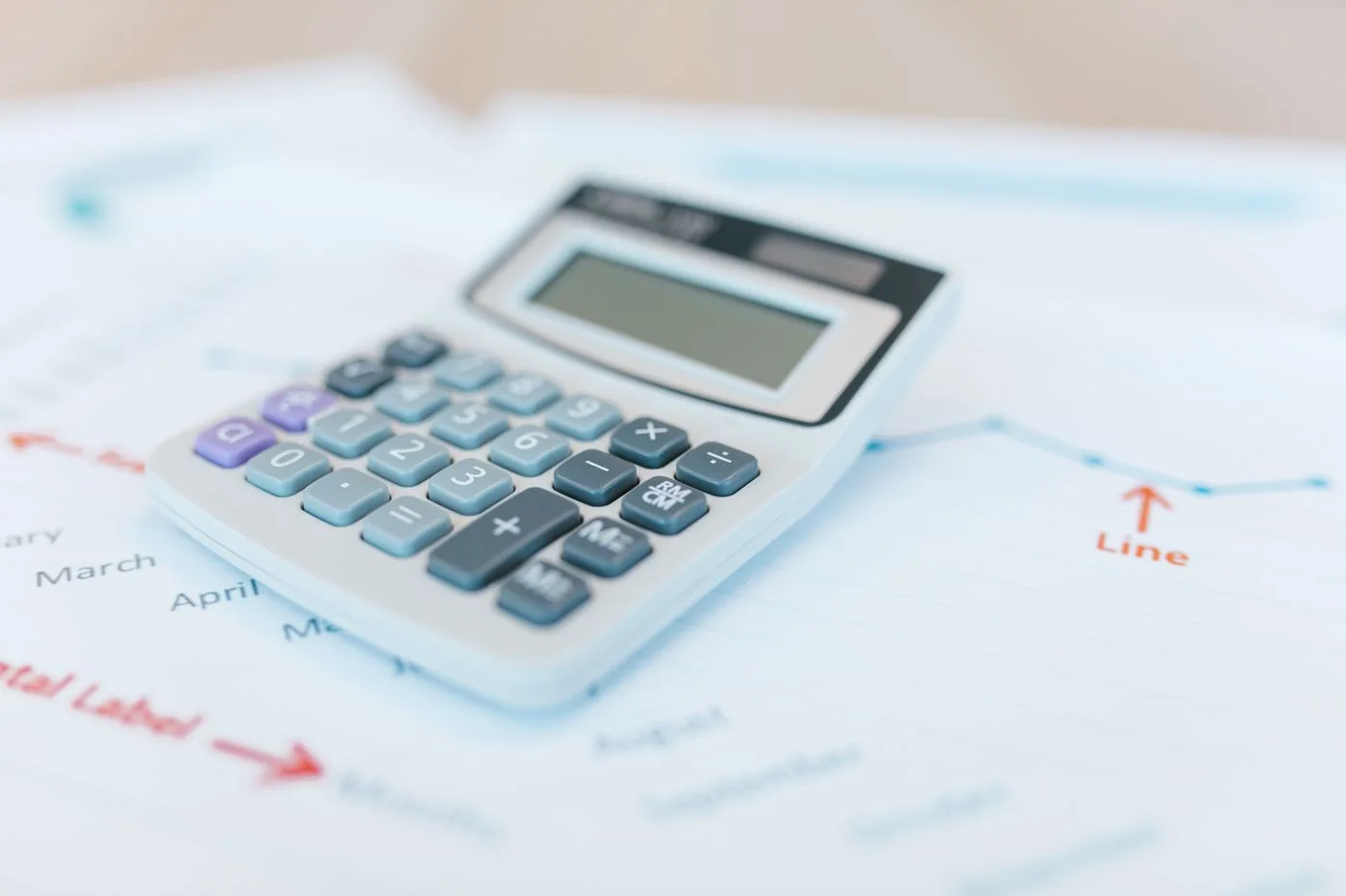 Close-up of a calculator on financial documents with graphs and analysis papers.